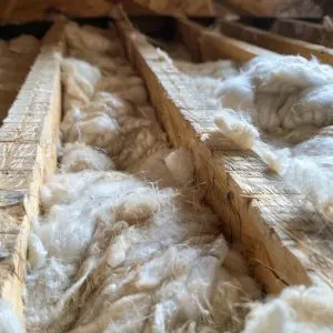 Close-up of fiberglass insulation being installed in an attic, illustrating effective ways to reduce heat loss and improve energy efficiency.