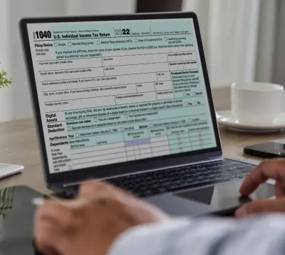 A person reviewing tax incentive forms on a laptop, highlighting potential rebates and savings for upgrading to an energy-efficient hybrid water heater.