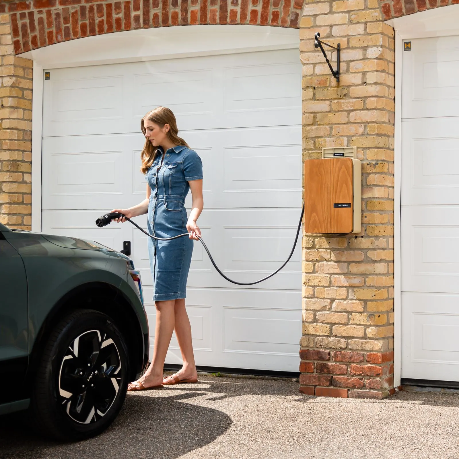 A homeowner charging an electric vehicle at a home EV charging station in a driveway