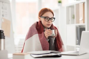 woman-huddled-under-blanket-and-drinking-out-of-mug